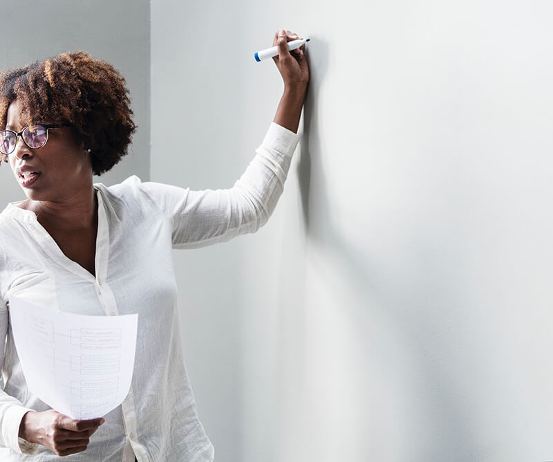 Woman writing ideas on whiteboard